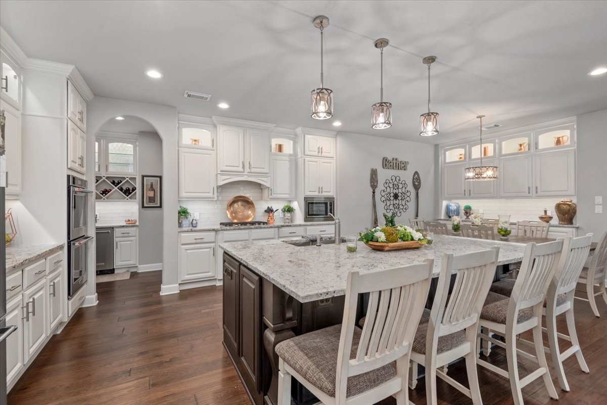 15519 Stallion Point Circle Cypress, TX 77429 - Photo 8 of 37 Spacious kitchen featuring an expansive central island with seating, pendant lighting, white cabinetry, and stainless steel appliances