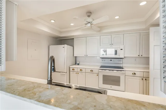 a kitchen with granite countertop a sink stainless steel appliances and white cabinets