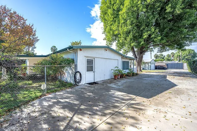 a view of a white house with a large tree and yard
