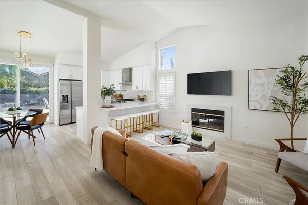 a living room with furniture a fireplace a flat screen tv and a large window