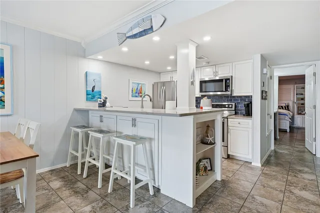a kitchen with kitchen island white cabinets and stainless steel appliances