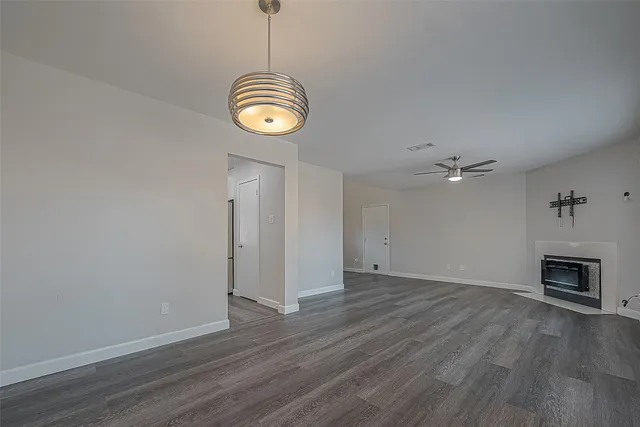 an empty room with wooden floor a chandelier and entryway