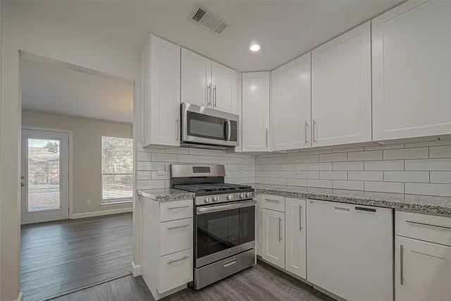 a kitchen with white cabinets stainless steel appliances and sink