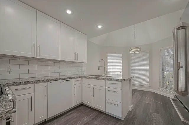 a kitchen with a sink dishwasher and white cabinets with wooden floor