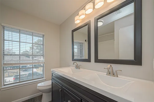 a bathroom with a granite countertop sink a toilet and a mirror