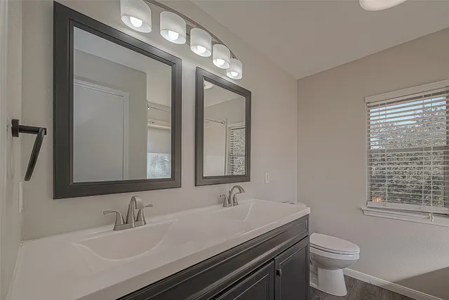 a bathroom with a granite countertop sink a toilet and a mirror