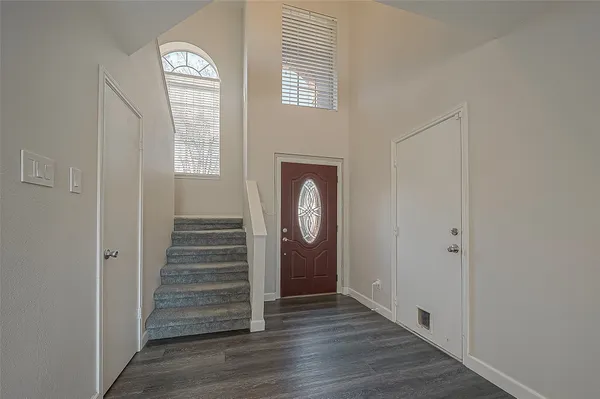 an empty room with wooden floor closet and windows