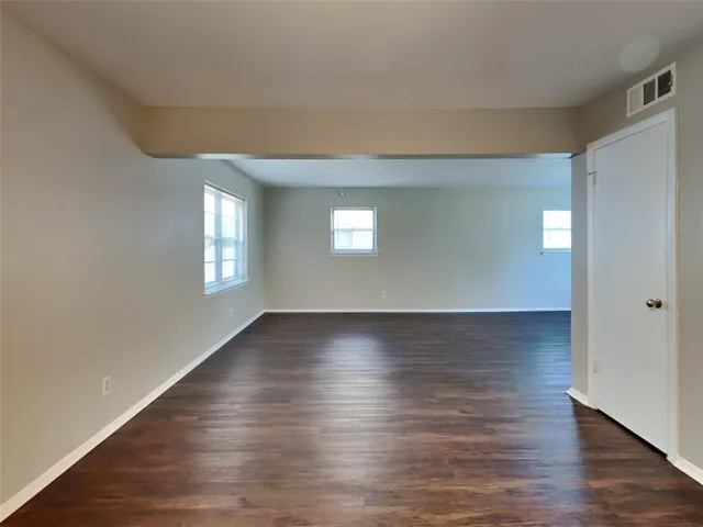 a view of an empty room with window and wooden floor