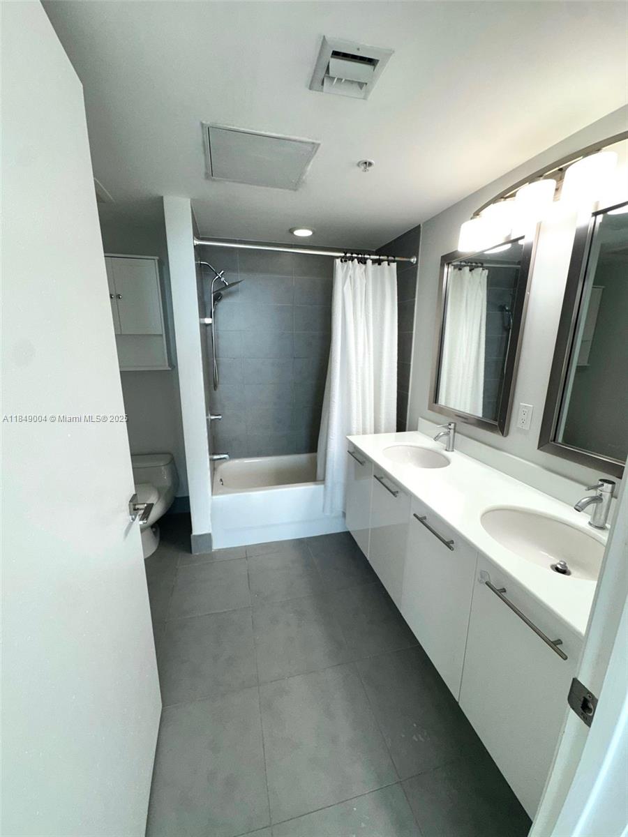 92 Southwest 3rd Street, Unit 3608 Miami, FL 33130 - Photo 16 of 24 a bathroom with a double vanity sink and mirror with bathtub