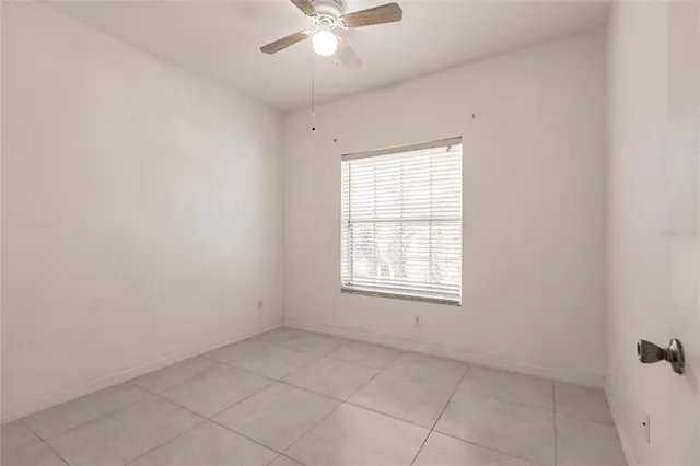an empty room with chandelier fan and windows