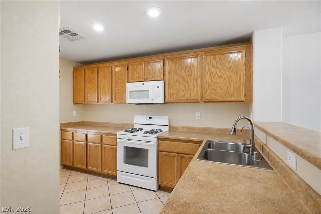 1172 Gecko Road Henderson, NV 89002 - Photo 4 of 30 A functional kitchen features warm wood cabinetry and durable countertops, ready for daily culinary endeavors.
