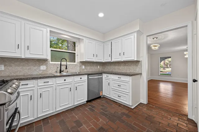 a kitchen with stainless steel appliances granite countertop a stove a sink and white cabinets