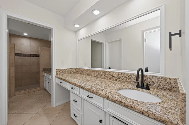 a bathroom with a granite countertop sink a mirror and shower