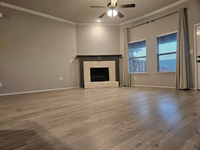 an empty room with wooden floor fireplace and windows