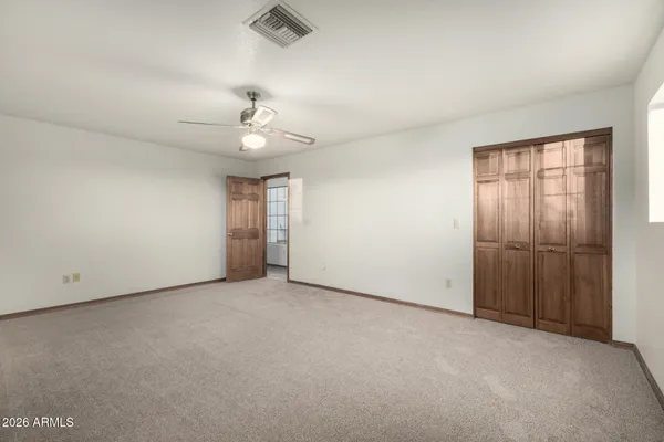 an empty room with chandelier fan and windows