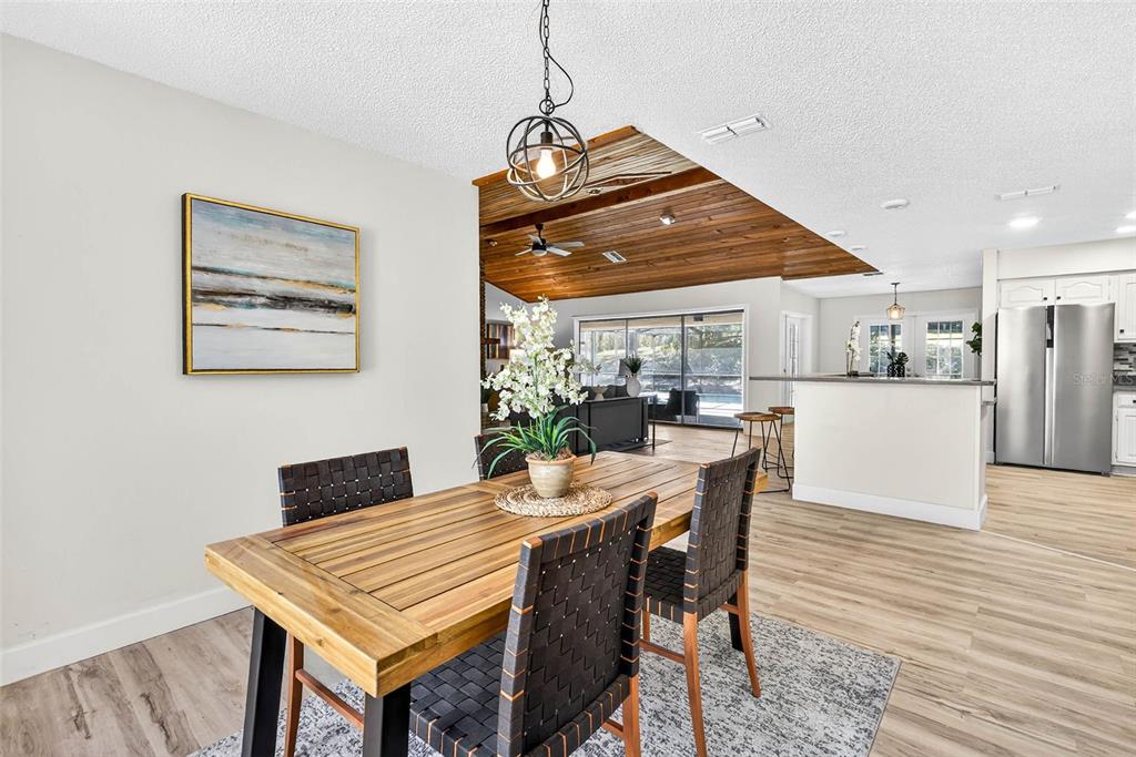 14252 Trinity Road Brooksville, FL 34614 - Photo 7 of 26 a dining room with wooden floor a chandelier a wooden table and chairs