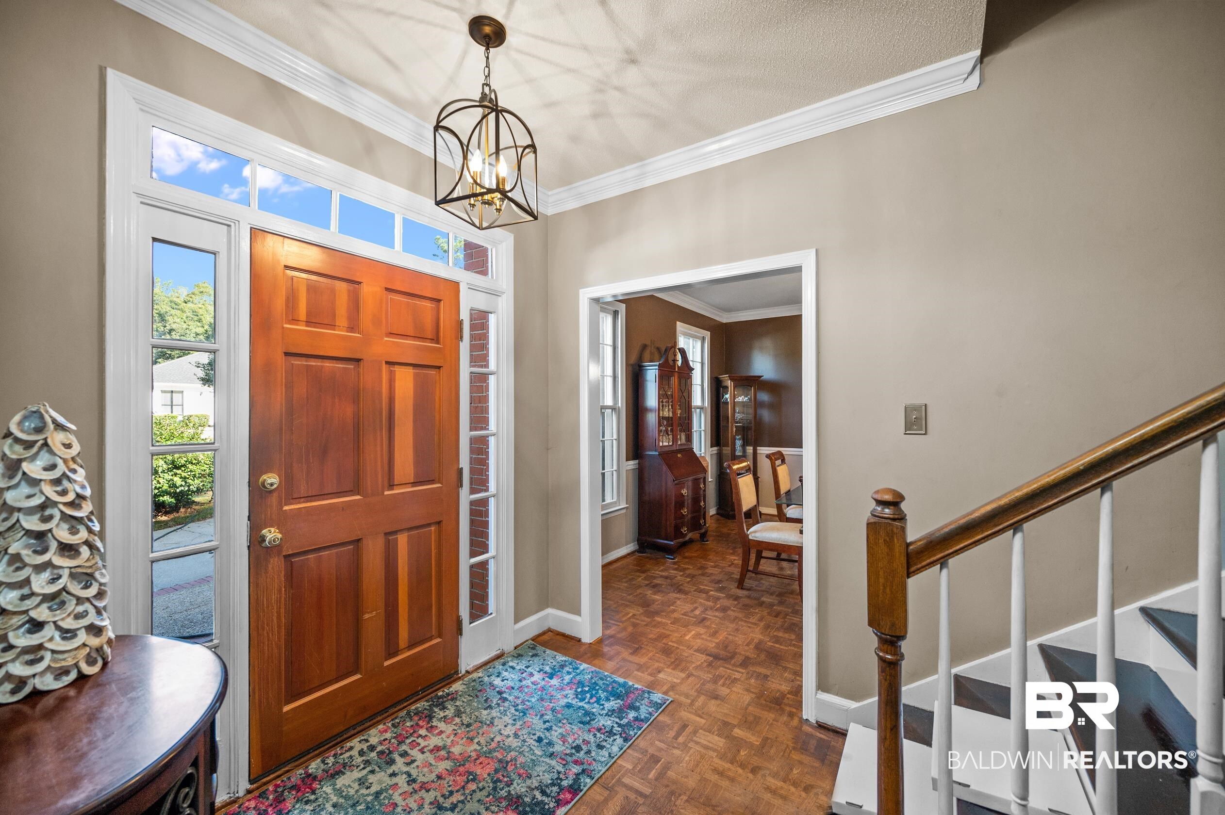 6705 Ridgeland Road South Mobile, AL 36695 - Photo 4 of 44 Entrance foyer featuring an inviting chandelier, crown molding, a textured ceiling, and dark parquet flooring