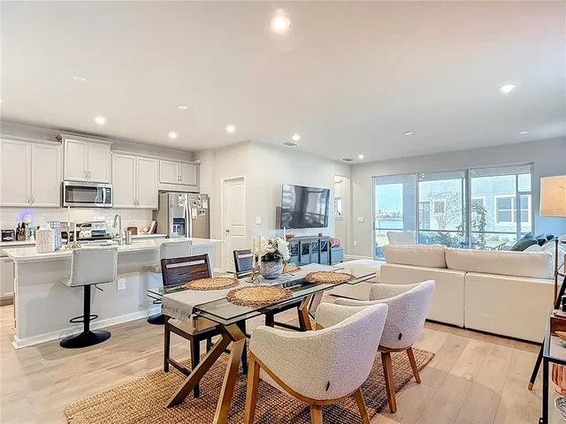 a living room with stainless steel appliances kitchen island granite countertop a sink a stove a dining table and chairs