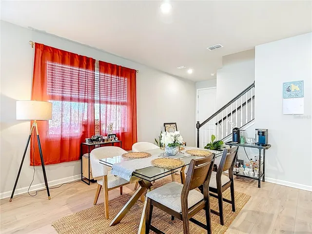 a kitchen with a refrigerator a stove cabinets and a dining table with wooden floor