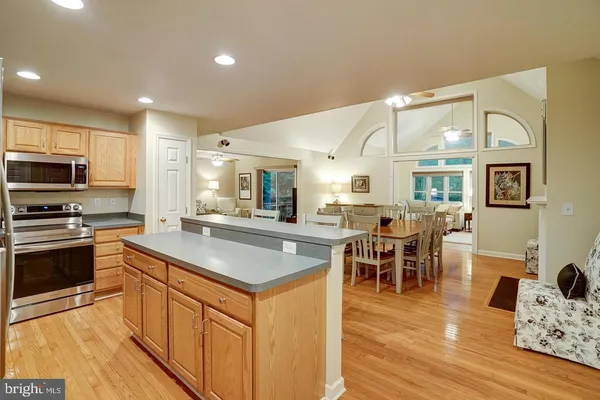 a kitchen with stainless steel appliances granite countertop a stove top oven a sink dishwasher a dining table and chairs with wooden floor