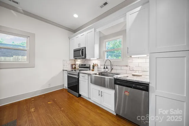 a kitchen with stainless steel appliances granite countertop a stove top oven a sink dishwasher and a refrigerator