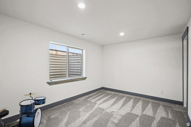 1588 West Rim Rock Drive Stockton, UT 84071 - Photo 31 of 61 Room featuring a patterned carpet, recessed lighting, and a window with a corrugated metal window well
