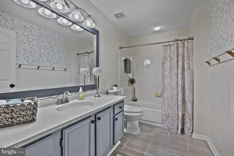 a bathroom with a granite countertop sink a toilet a mirror and shower