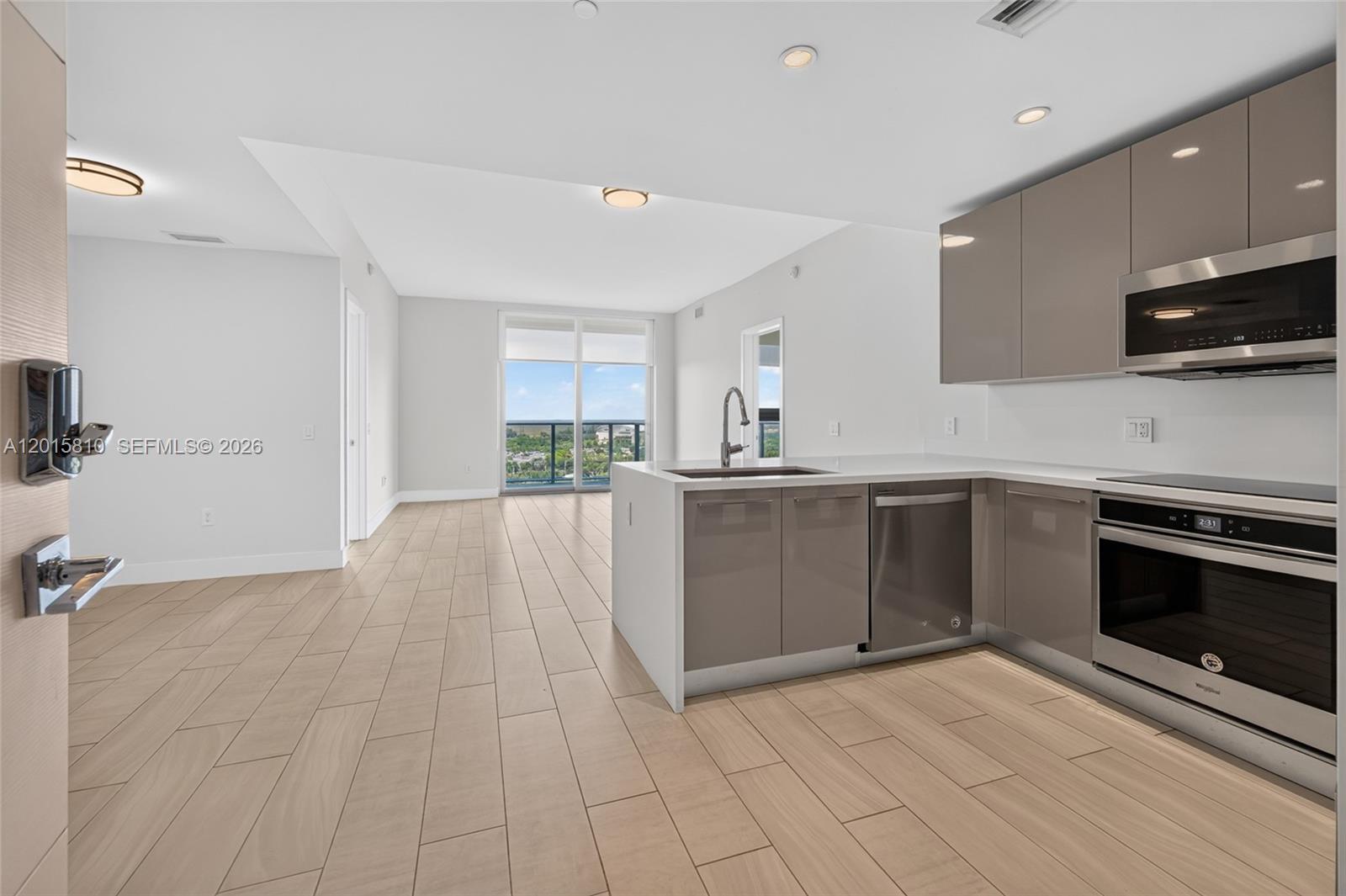2000 Metropica Way, Unit 1902 Sunrise, FL 33323 - Photo 4 of 40 a kitchen with stainless steel appliances kitchen island granite countertop a stove a sink and a microwave