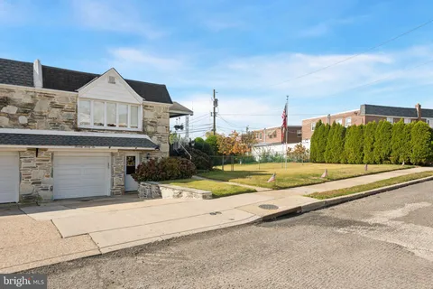 a view of a house with a small yard and large trees