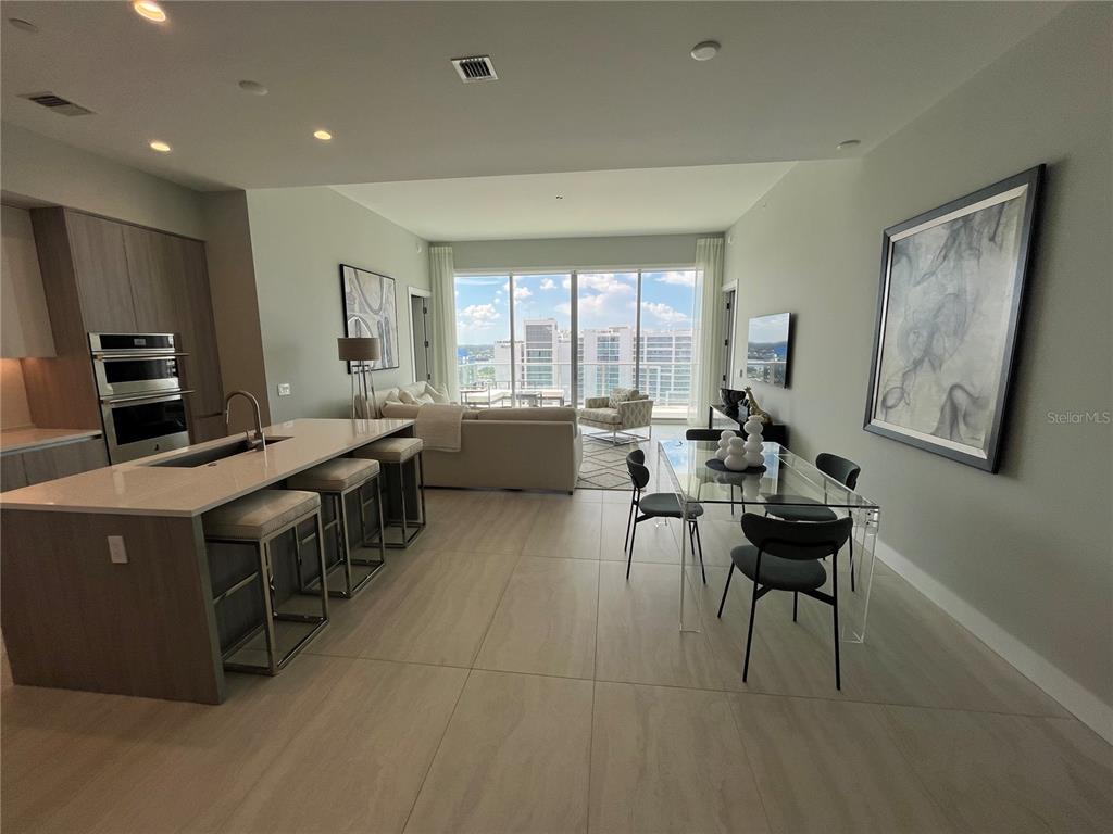 301 Quay Commons, Unit 1808 Sarasota, FL 34236 - Photo 4 of 12 a kitchen with stainless steel appliances a stove a sink a microwave and chairs