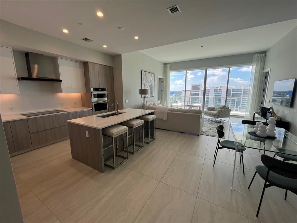 301 Quay Commons, Unit 1808 Sarasota, FL 34236 - Photo 5 of 12 a kitchen with kitchen island granite countertop a sink counter top space appliances and a large window