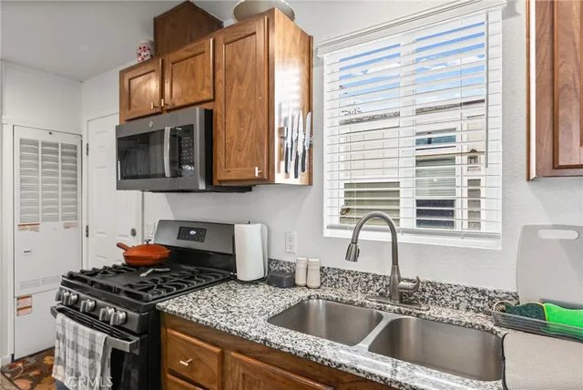 a kitchen with stainless steel appliances granite countertop a sink a stove and a microwave