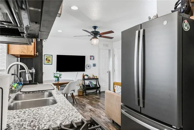 a living room with furniture a flat screen tv and a refrigerator