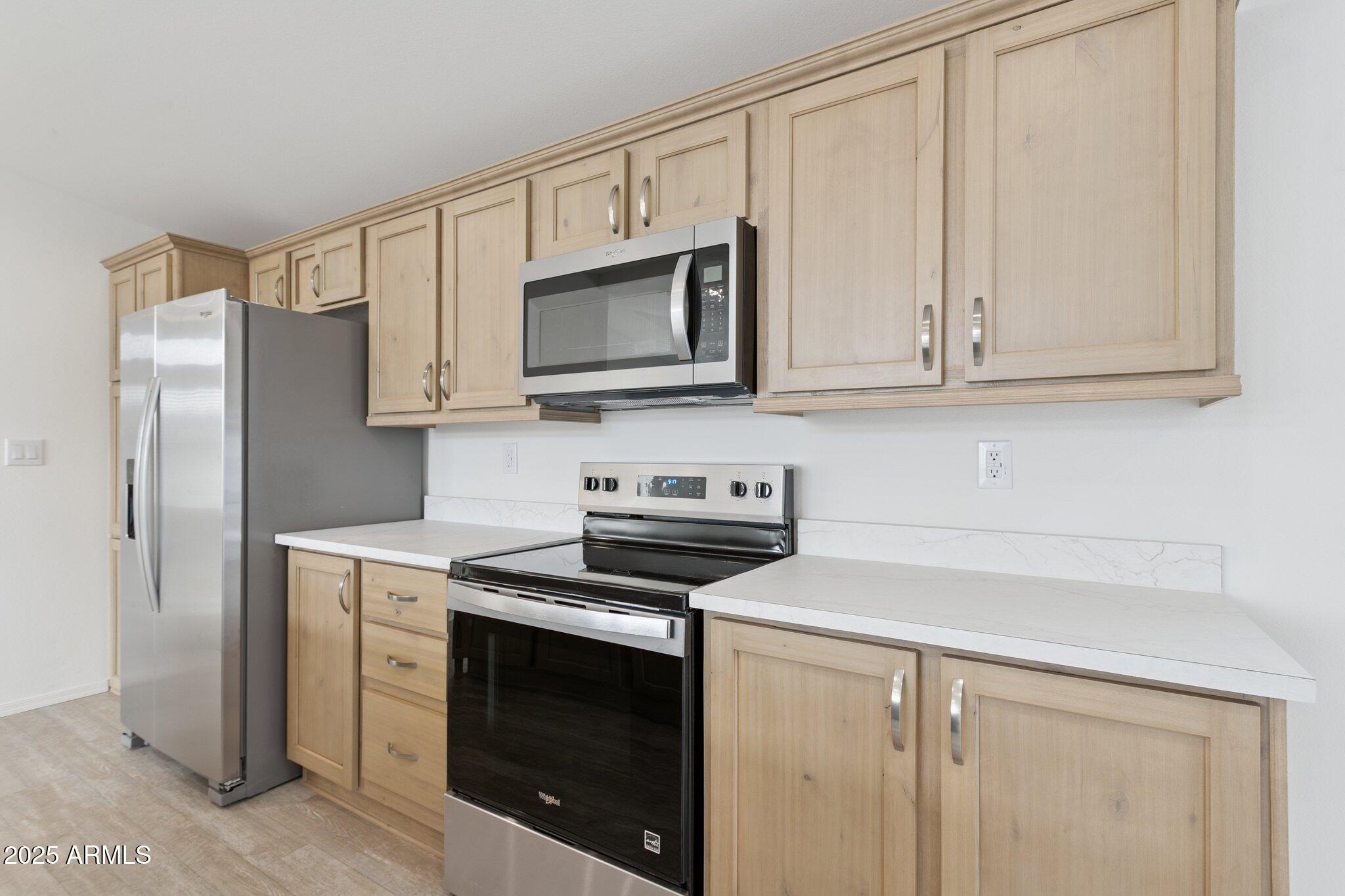 755 North Ralston Road Maricopa, AZ 85139 - Photo 21 of 34 a kitchen with stainless steel appliances granite countertop white cabinets a microwave a sink and a refrigerator