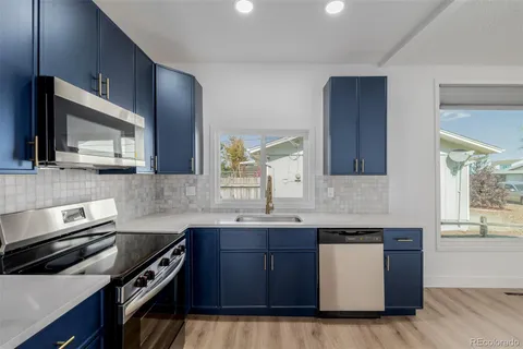 a kitchen with kitchen island granite countertop a sink cabinets and stainless steel appliances