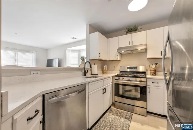 a kitchen with stainless steel appliances a stove a sink and a refrigerator