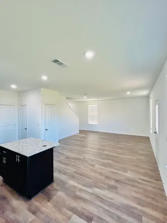 a view of an empty room with wooden floor and staircase