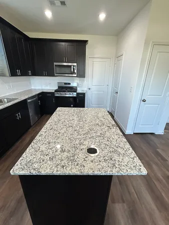 a kitchen with kitchen island granite countertop a sink stove and refrigerator