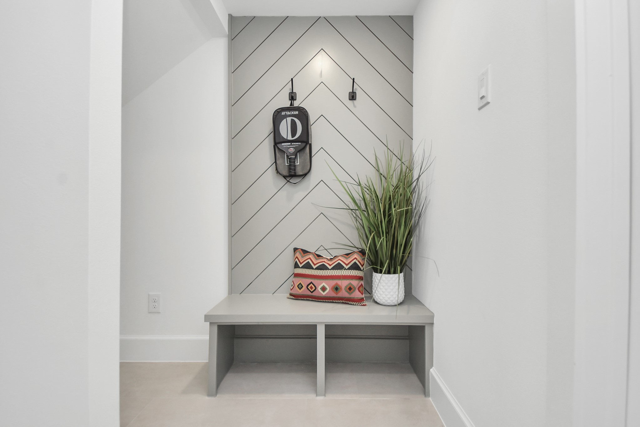 927 Fisher Street, Unit B Houston, TX 77018 - Photo 4 of 47 Step into this modern, minimalist nook featuring a sleek bench against chevron-patterned wall paneling. Accented with a decorative pillow and a potted plant, this space combines style and functionality, making it an inviting entryway or practical mudroom for everyday living.