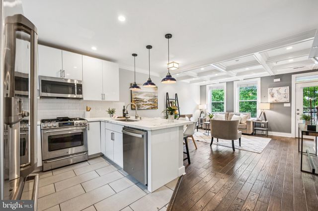 a kitchen with stainless steel appliances kitchen island granite countertop a stove a sink a dining table and chairs with wooden floor