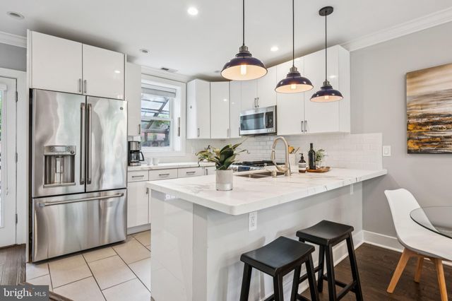 a kitchen with stainless steel appliances granite countertop a sink a stove a refrigerator and island with wooden floor