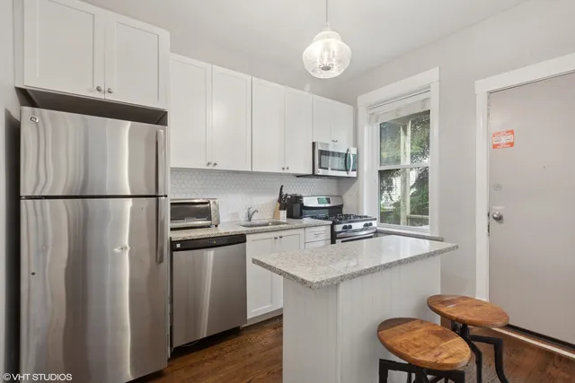 a kitchen with stainless steel appliances granite countertop a sink refrigerator stove and white cabinets
