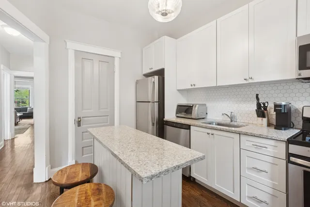 a kitchen with stainless steel appliances granite countertop a sink a stove a refrigerator and white cabinets with wooden floor