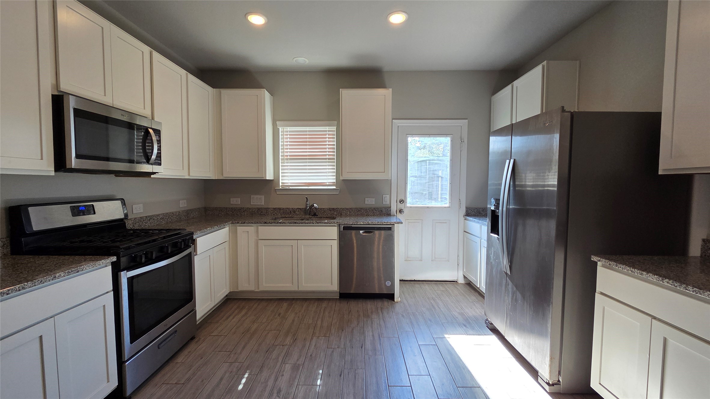 914 Redinger Ridge Drive Houston, TX 77336 - Photo 3 of 16 a kitchen with stainless steel appliances granite countertop white cabinets a refrigerator a sink a stove a microwave and wooden floors