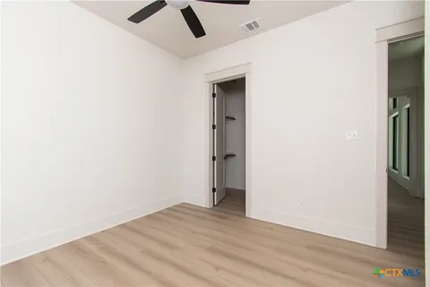 an empty room with wooden floor and hallway