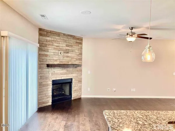 a view of an empty room with a fireplace and wooden floor