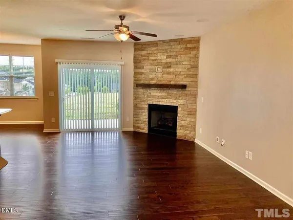 a view of an empty room with wooden floor and a fireplace