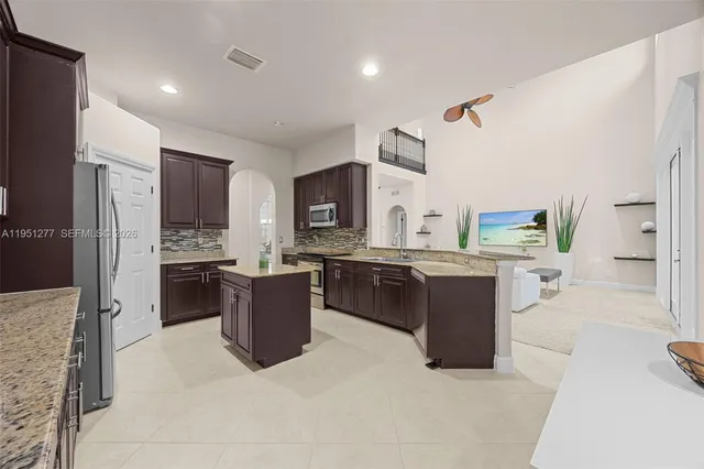 a large kitchen with a large counter top space a sink stainless steel appliances and cabinets