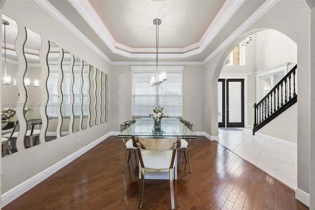 a dining room with wooden floor a chandelier a wooden table and chairs