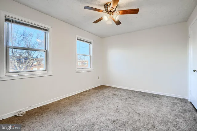 an empty room with windows and fan
